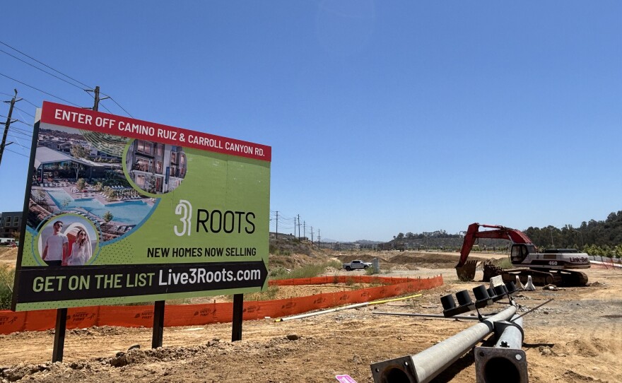 Construction equipment sits next to a billboard advertising the new 3Roots community in Mira Mesa, July 7, 2025.