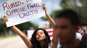 A protester in front of Sen. Marco Rubio's Doral, Fla., office in 2013 urges Rubio to stop opposing the inclusion of lesbian, gay, bisexual and transgender families in the Senate's immigration bill.
