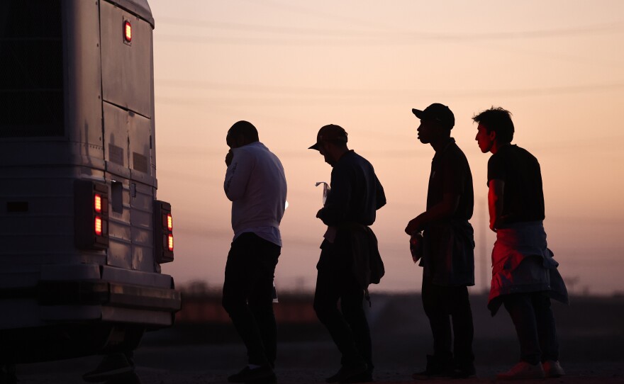 Immigrants seeking asylum wait to board a bus to a U.S. Border Patrol processing center, after crossing into Arizona from Mexico, on Thursday in Yuma, Ariz.