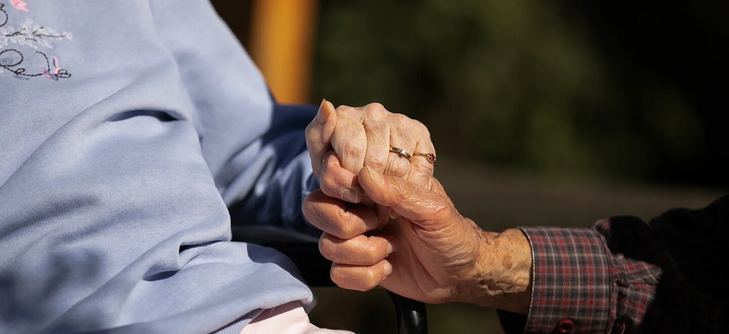 An elderly couple hold hands at nursing home in California in 2021.
