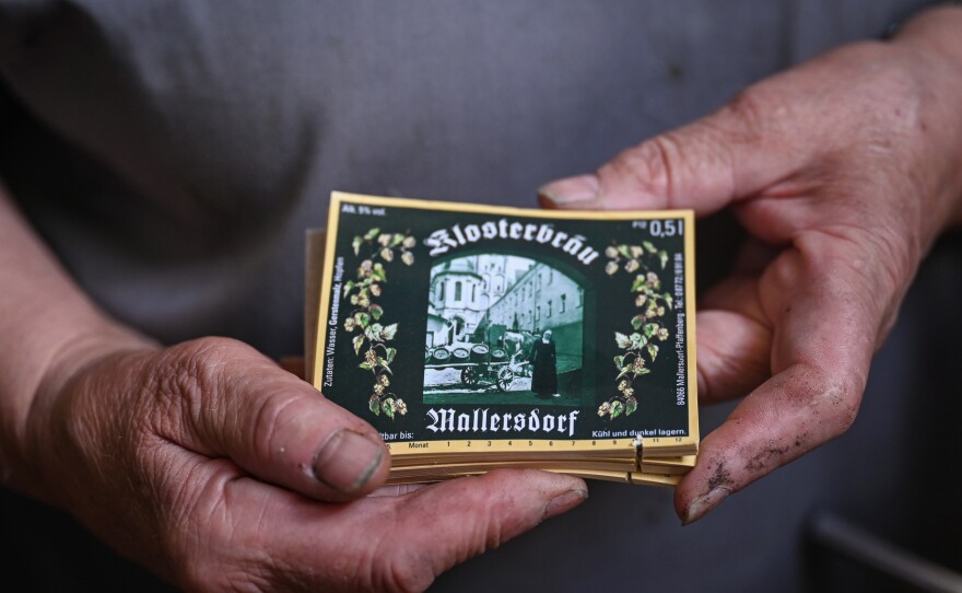 Sister Doris holds labels of the beer bottles with a painting of the former nun who was running the brewery.