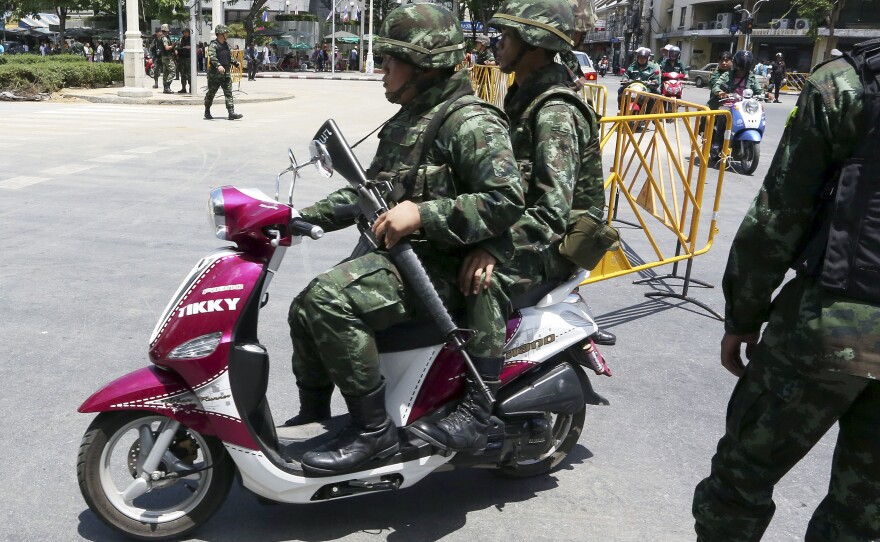 Thai soldiers patrol on a scooter Friday near the Democracy Monument in Bangkok. Thailand's ruling military summoned leaders of the ousted government to meetings today. Restrictions on TV broadcasts have led Thai citizens to ask for more variety.
