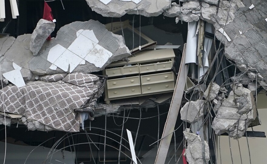 A bed and a chest of drawers dangle from the ruins on Thursday.