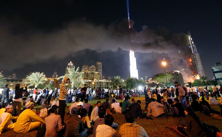 People watch the Address Downtown hotel burning on Thursday after a huge fire ripped through the luxury hotel in Dubai.