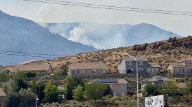 Smoke billows in the distance as a wildfire burns in Reno, Nev., Sunday, August 23, 2026. (AP Photo/Haven Daley)