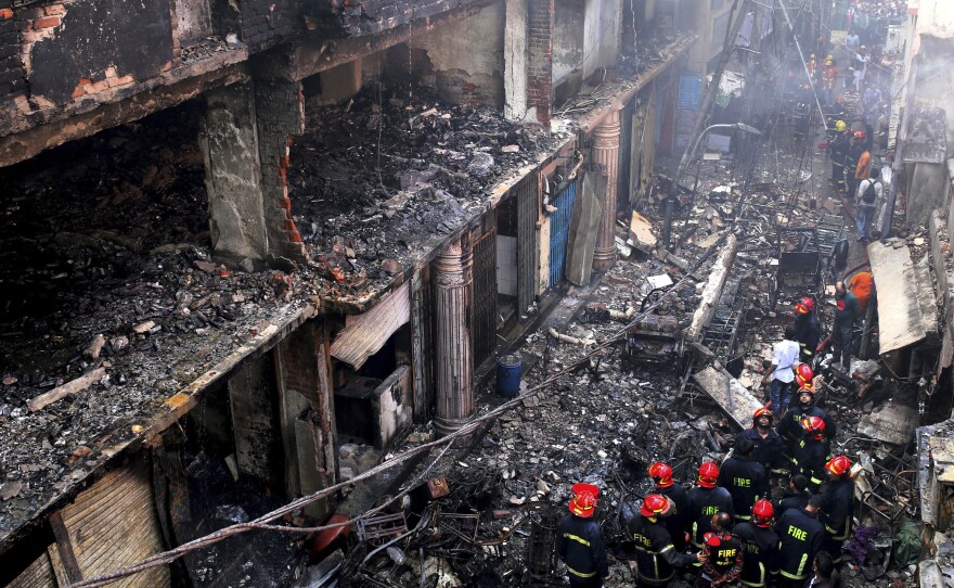 Locals and firefighters gather around buildings that caught fire late Wednesday in Dhaka, Bangladesh, on Thursday, killing dozens of people.