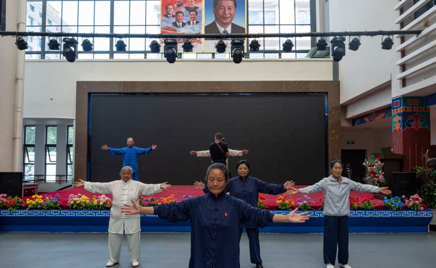 Elderly residents perform tai chi near the portrait of Chinese President Xi Jinping and other Chinese leaders at the Chengguan District Day Care Center for the Elderly in western China's Tibet autonomous region on July 20, 2026, as seen during a government-organized visit for foreign journalists.