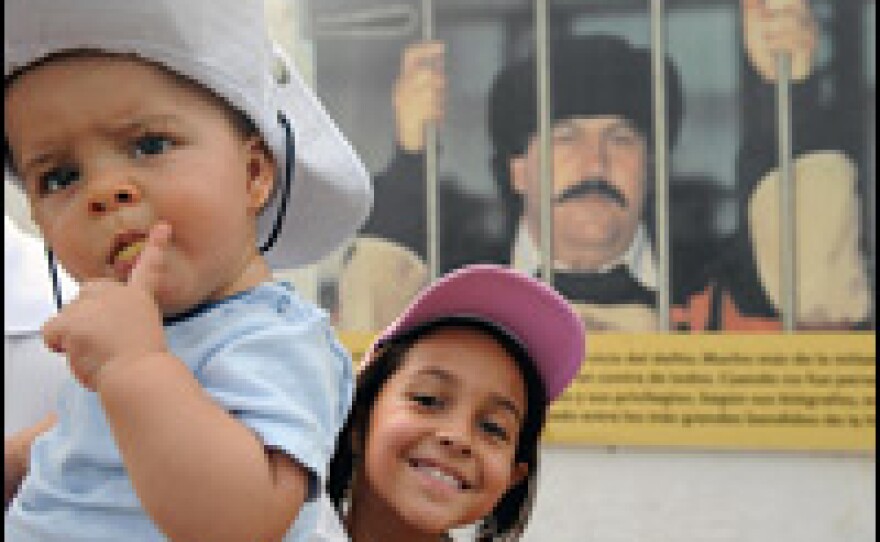 Children pose for a photograph inside Escobar's destroyed mansion. Until his death, Escobar (shown in the background) was the richest drug trafficker in history.
