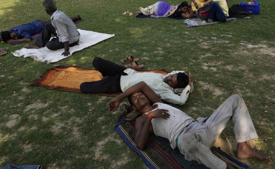 People rest in the shade of a tree on a hot summer afternoon in Lucknow in the central Indian state of Uttar Pradesh, on Thursday. Severe heat wave conditions are sweeping north and western parts of India.