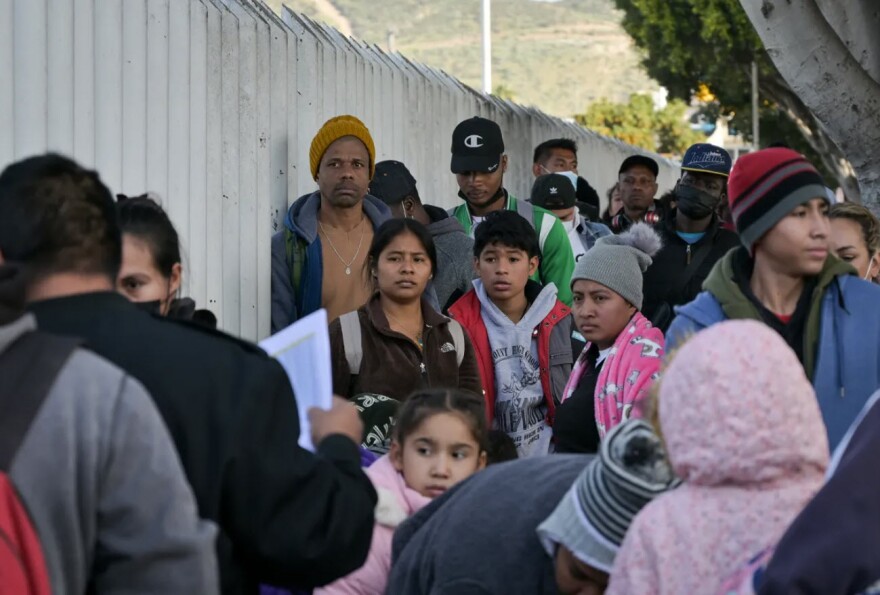 Migrants form a line to enter the U.S. and seek asylum through El Chaparral port of entry in San Diego at the Mexico border on Dec. 22, 2022.