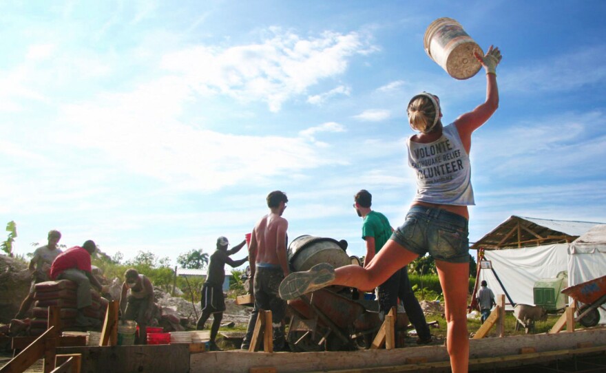 In Haiti after the earthquake, volunteers with All Hands toss buckets from the cement mixer back to the sand piles for a quick refill.