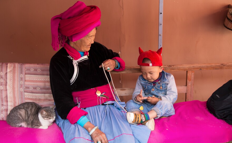 Zhaba Songding's grandmother, Ani Ciru, 77, sits with Zhaba's son Luosang Nyima, 2, and cat in their courtyard.