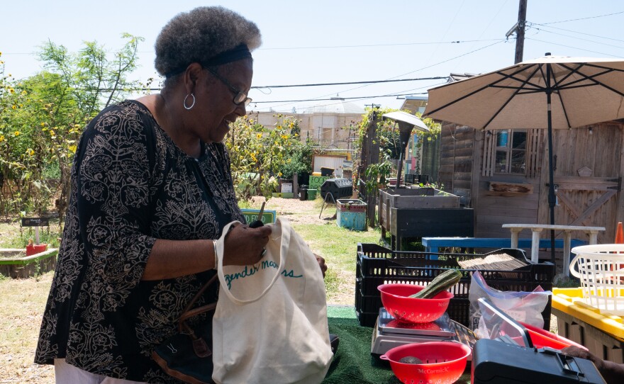 Diane Moss fills her tote bag with fresh produce after checking out with West at the mobile market.