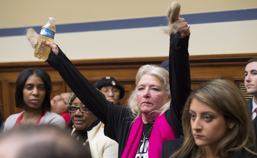 Flint resident Glaydes Williamson holds up a bottle of water from the city and hair pulled from her drain during a House Oversight and Government Reform Committee hearing in Washington, D.C., in February.