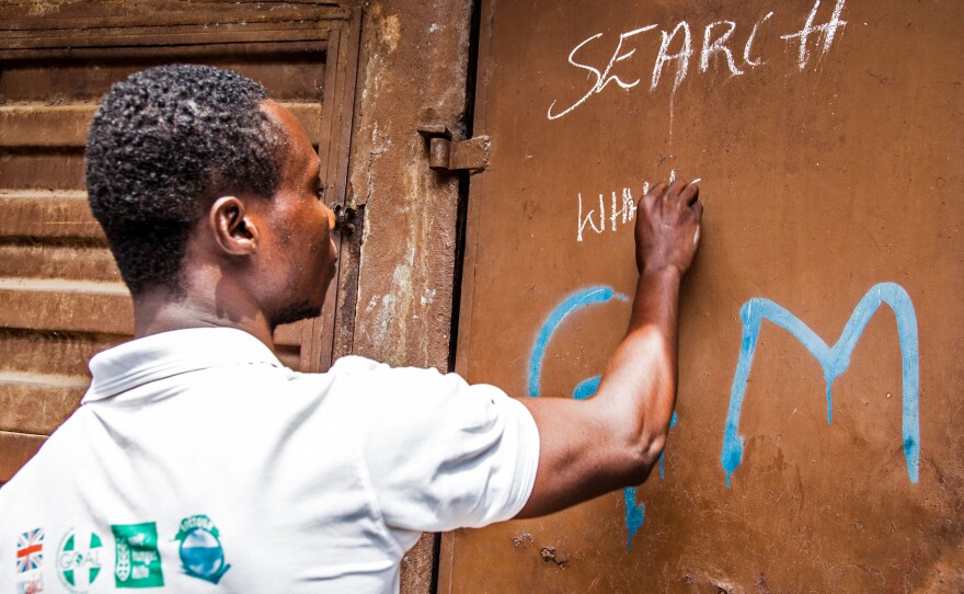 A health worker marks a house as free of Ebola while going door to door, looking for infected people in Freetown, Sierra Leone.