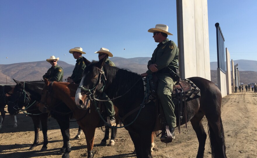 Border Patrol agents ride past border wall prototypes, Oct. 26, 2017.