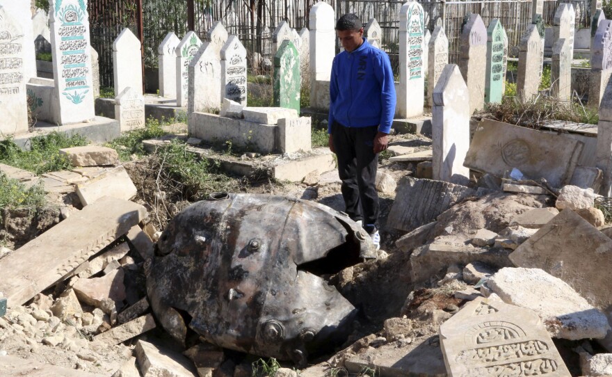 A man looks at an unexploded barrel bomb that landed in a cemetery after being dropped by forces loyal to Syria's President Bashar Assad in the northern Syrian city of Aleppo on Thursday.