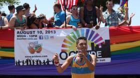 A San Diego Pride Parade participant dances alongside a float on University Avenue, July 13, 2013.