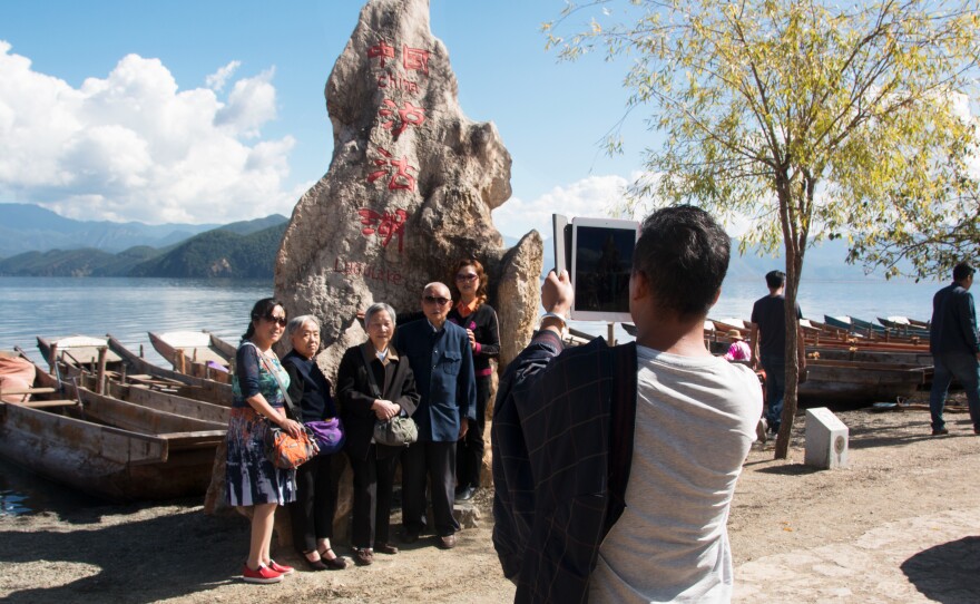 Tourists take photos by the water in Lugu Lake in southwest China. The area is home to the Mosuo ethnic group, which has one of the world's relatively rare matrilineal societies.