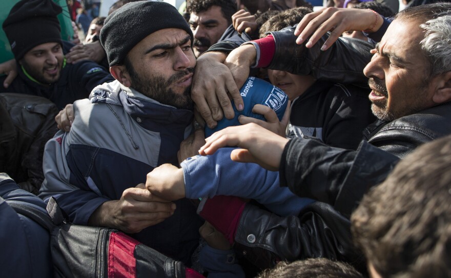Refugees scrabble among each other as they stage a protest Tuesday along the Greek-Macedonia border near Idomeni.