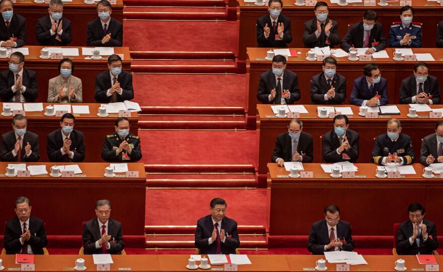 China's President Xi Jinping (C) applauds with other leaders and delegates after they voted on changes to Hong Kong's election system during the closing session of the National People's Congress at the Great Hall of the People in Beijing on March 11, 2021.