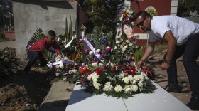Juan, right, who has been arrested in connection with the disappearance and murder of Marbella Valdez, puts a floral arrangement on her grave, alongside her ex-boyfriend Jairo Solano, during her funeral at a cemetery in Tijuana, Mexico, Friday, Feb. 14, 2020.