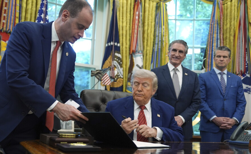 White House staff secretary Will Scharf hands President Donald Trump an executive order to sign regarding nuclear energy in the Oval Office of the White House, Friday, May 23, 2025, in Washington.