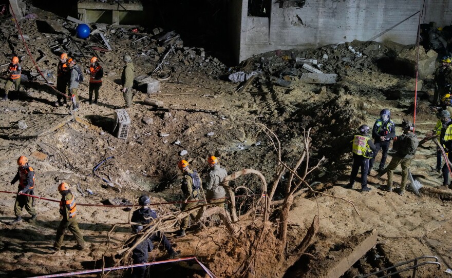 Israeli security forces and rescue teams inspect the crater left by an Iranian missile in Arad, southern Israel, Sunday, March 22, 2026.