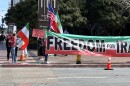 The San Diego Iranians Group stands around a large 'Freedom for Iran' sign holding flags and signs in honor of International Women's Day in Downtown San Diego on March 8, 2023.