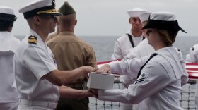 Cmdr. Jay M. Steingold, executive officer of the amphibious assault ship USS Peleliu (LHA 5), receives remains from Quartermaster Seaman Apprentice Sarah Higginbotham during a burial at sea ceremony. 
