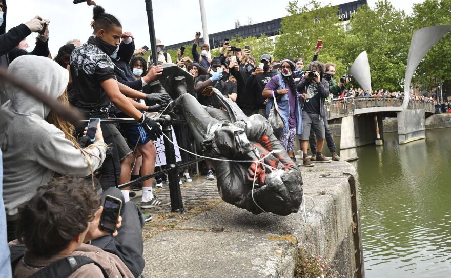 Protesters throw a statue of slave trader Edward Colston into Bristol Harbor on Sunday during a Black Lives Matter protest in England.