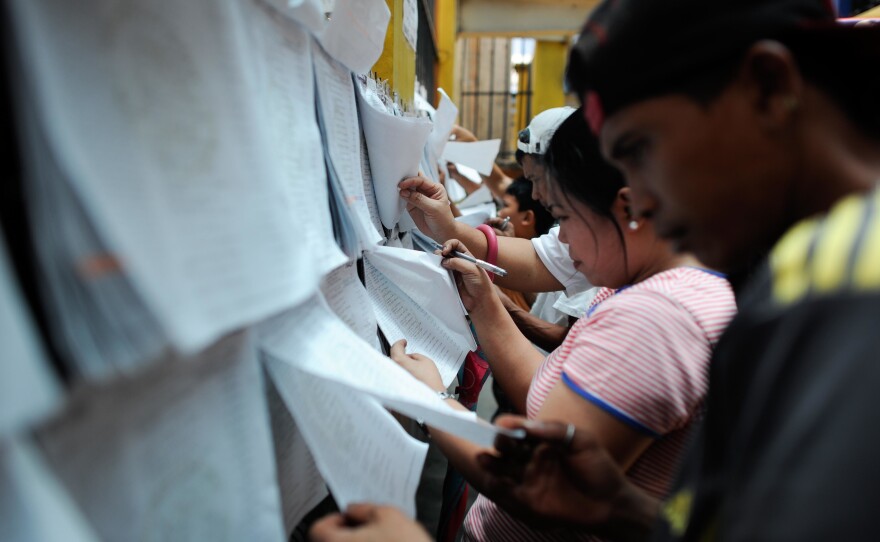 Voters look for their names and assigned precincts at a public elementary school on Sunday in Manila.
