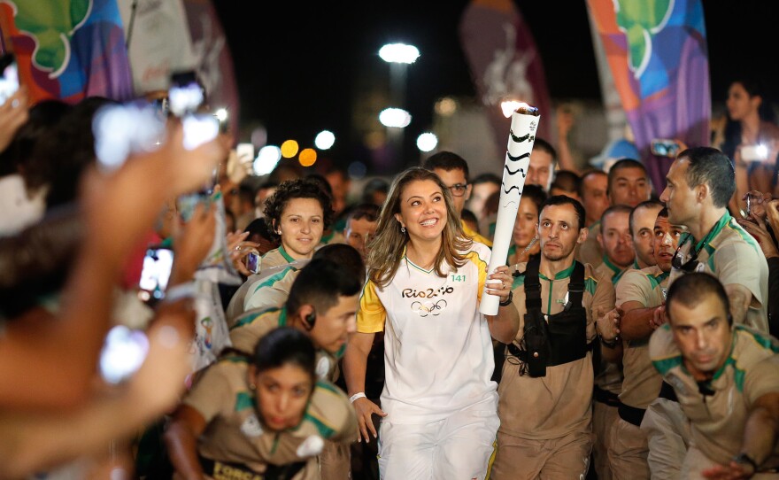The Olympic flame gets a lift from former Brazilian volleyball player Leila Barros, who took part in this month's torch relay. The games are set to begin on Aug. 5.
