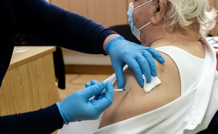 A healthcare worker administers a dose of the coronavirus vaccine to an elderly at a health center in the Cypriot coastal city of Limassol on February 8, 2021.