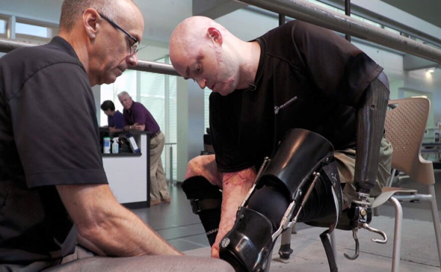 Lt. Col. Bryan Forney, USMC, puts on his Intrepid Dynamic Exoskeletal Orthosis (IDEO) brace with the help of John Fergason, chief prosthetist at the Center for the Intrepid at Brooke Army Medical Center in San Antonio, Texas. The IDEO brace, invented at the CFI, enables patients to walk, and sometimes even run, despite severely injured legs and ankles.