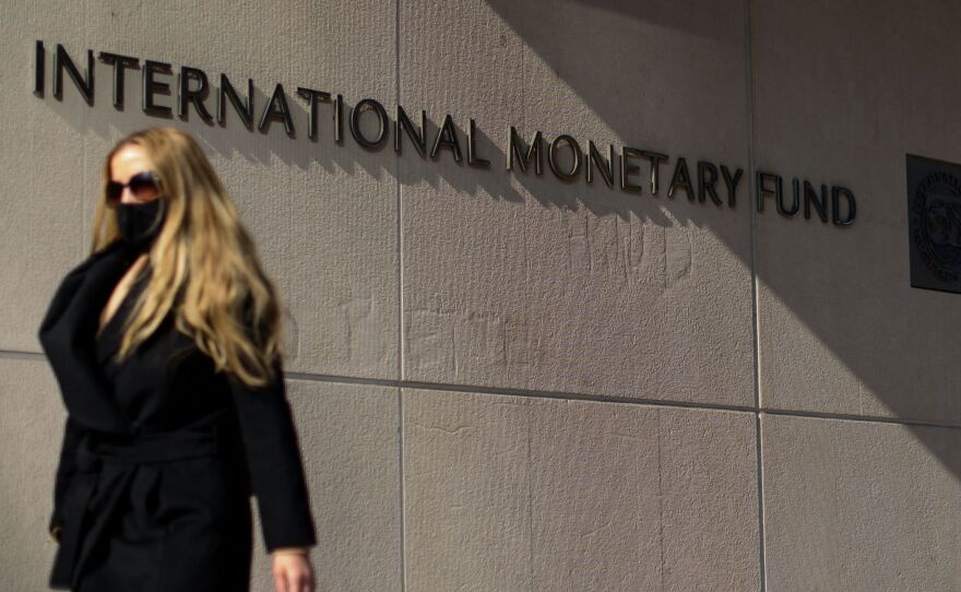 A woman walks past the International Monetary Fund headquarters building in Washington, D.C. on April 5. The IMF on Tuesday raised its forecasts for both the U.S. and the global economies.