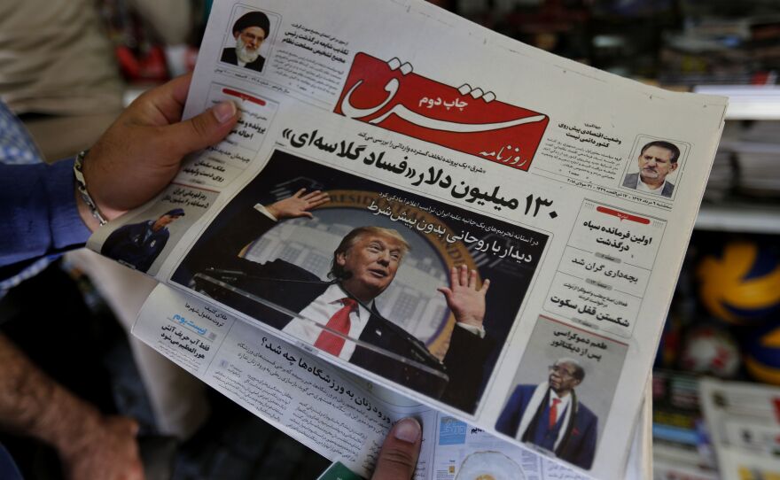 A man in Tehran looks at a newspaper with a picture of President Trump on the front page on Tuesday. Iran's currency traded at a fresh record-low of 119,000 to the dollar today, a loss of nearly two-thirds of its value since the start of the year as U.S. sanctions loom. Trump says he's willing to meet with Iranian leaders, but Iran doesn't seem eager to sit down.