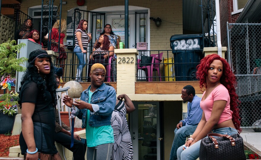 Ruby Corado (top, center) sits on the porch of Casa Ruby, a drop-in and service center for transgender people in Washington, D.C., while many of her clients, friends and employees hang out in front.  Corado also runs another venue nearby, a house for homeless transgender adults.