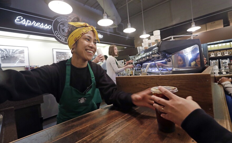 Barista Sarah Dacuno serves a customer at a Starbucks, commonly referred to as the original Starbucks, in the Pike Place Market in Seattle Tuesday, May 29, 2018. 