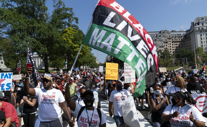 Demonstrators walk during a march for voting rights on Saturday in Washington, D.C., marking the 58th anniversary of the March on Washington for Jobs and Freedom. The Willard InterContinental hotel, where Israeli Prime Minister Naftali Bennett was staying with his entourage, is on the right.