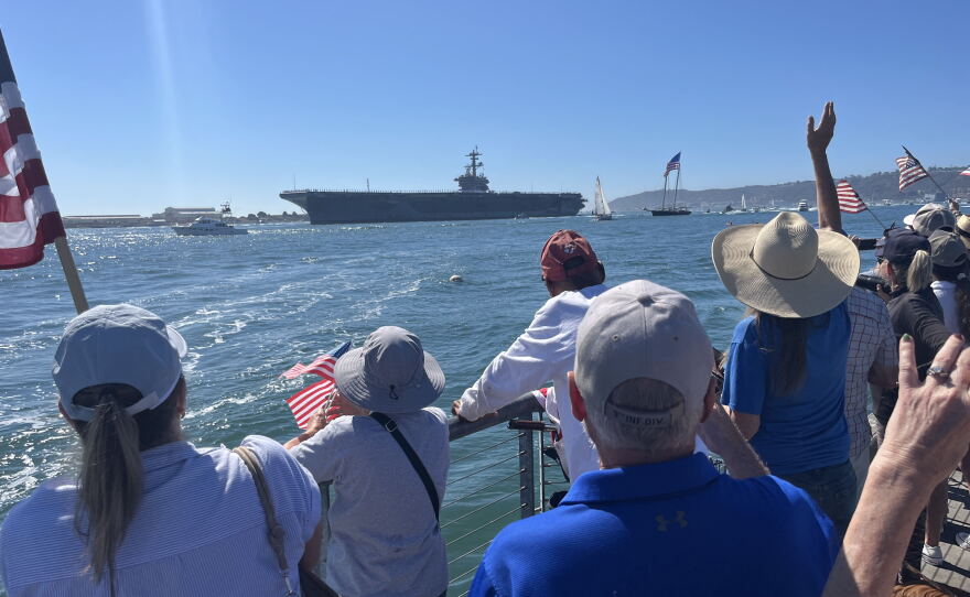 People gather with American flags along Shelter Island's shoreline ahead of the USS Lincoln's arrival, Oct. 8, 2026.