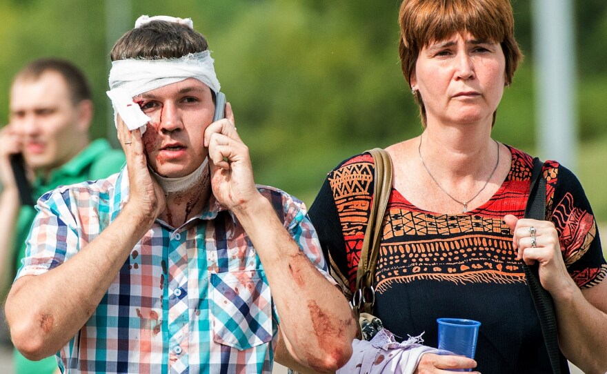 An injured man who was on a subway train that derailed in Moscow Tuesday talks on his phone after being treated by paramedics. Officials say around 150 people were injured, and at least 19 were killed, in the incident.