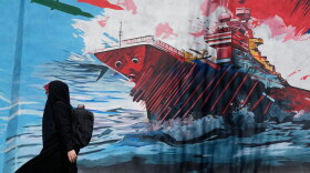 A woman walks past a mural depicting a U.S. aircraft carrier under missile attack in downtown Tehran, Iran, on June 8.
