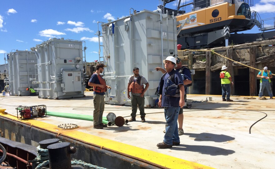 Tugboat crew members Ed Pattison (from left), Tony Awed and Dennis Wasiewski prepare a barge carrying electrical transformers to leave the Port of Albany for a voyage on the Erie Canal.