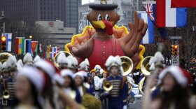 A balloon and marching band make its way down the Benjamin Franklin Parkway during a Thanksgiving day parade in Philadelphia.