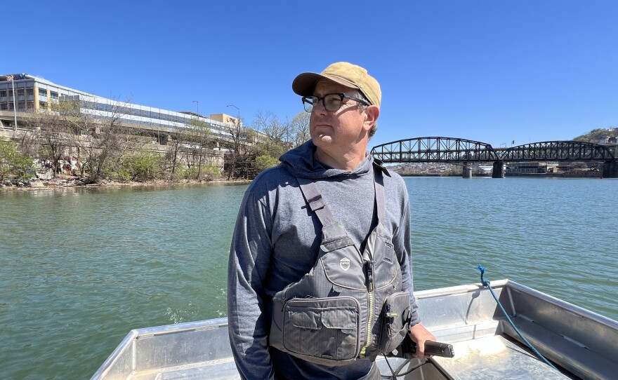Evan Clark steers a boat on the Monongahela River, one of two tributaries that converge to form the Ohio River in Pittsburgh, PA. Clark works with Three Rivers Waterkeeper, an environmental nonprofit that works to protect the rivers.