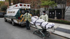 In this April 17, 2020 file photo, a patient is wheeled out of Cobble Hill Health Center by emergency medical workers in the Brooklyn borough of New York.