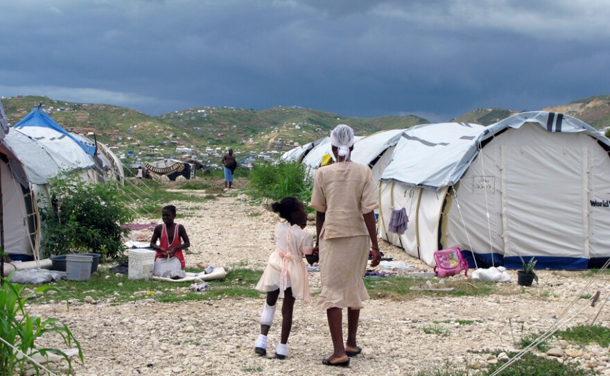 5-year-old Louisemie Antoine, who lost her left leg below the knee in the Jan. 12 earthquake, walks through Camp Corail just north of Port-au-Prince with her mother, Yvonne. More than 6,500 live in the camp in long lines of white tents.