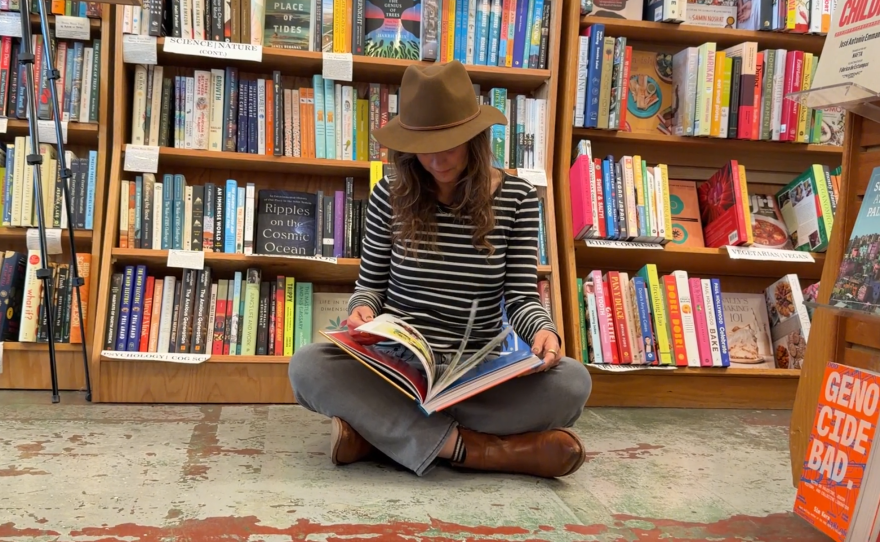 Britton Neubacher pages through a copy of "Plenty For All: The Art of Rick Fröberg," at The Book Catapult on Jan. 12, 2026.