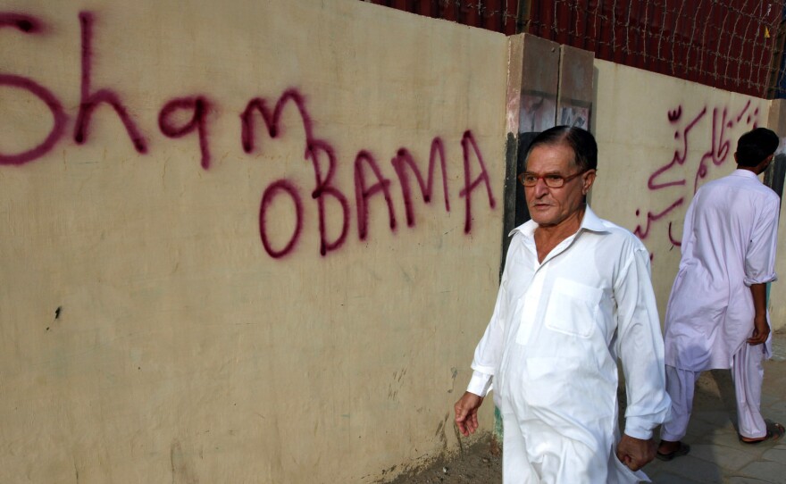 A Pakistani man walks past graffiti, which criticizes President Obama, on the wall outside the U.S. Consulate in Karachi in September 2011.